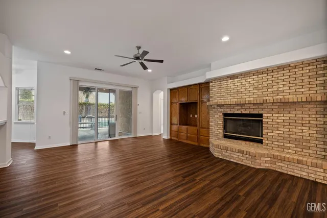 an empty room with a chandelier fan and windows