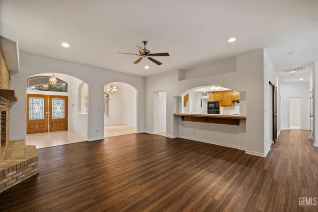 an empty room with wooden floor fan and windows