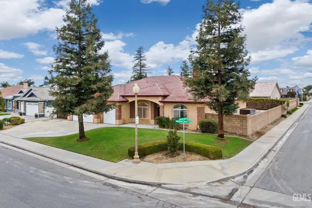 a view of a white house with a big yard and potted plants