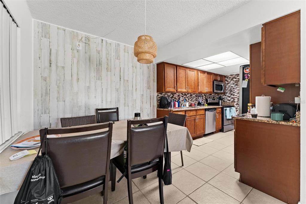 5201 Vineland Road, Unit 112 Orlando, FL 32811 - Photo 8 of 25 a kitchen with stainless steel appliances a table chairs and a refrigerator