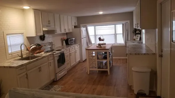 a kitchen with stainless steel appliances a sink a stove a refrigerator cabinets and dining table