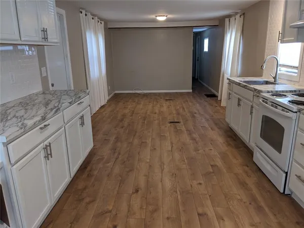 a view of a kitchen with wooden floor and electronic appliances