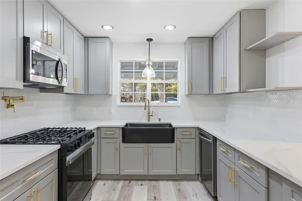 a kitchen with stainless steel appliances granite countertop a stove a sink and a microwave