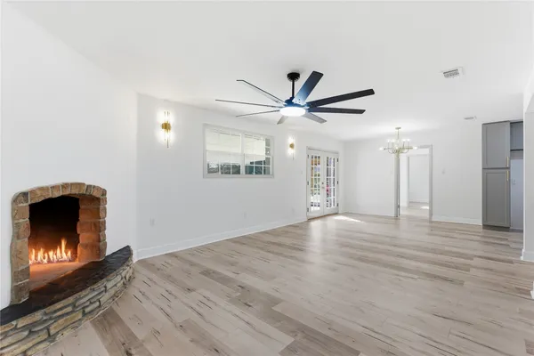 a view of an empty room with wooden floor and a fireplace