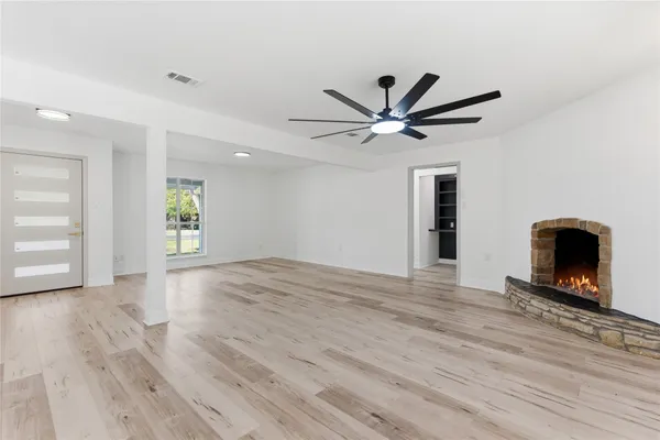a view of a livingroom with a fireplace a ceiling fan and wooden floor