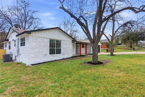 a backyard of a house with plants and large tree