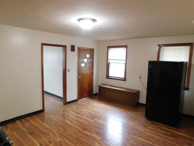 an empty room with wooden floor cabinet and windows