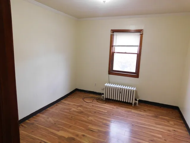 an empty room with wooden floor and a window