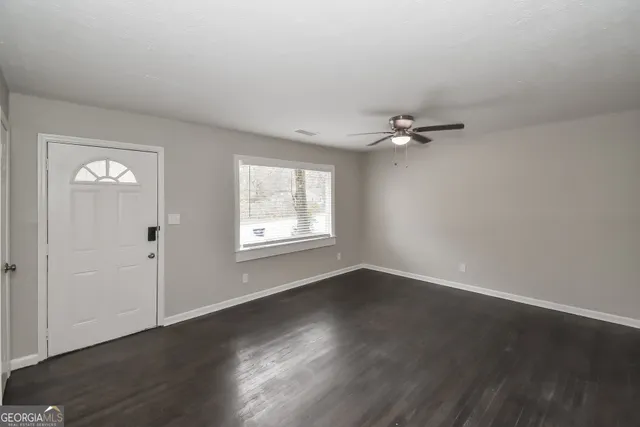 a view of an empty room with a window and wooden floor