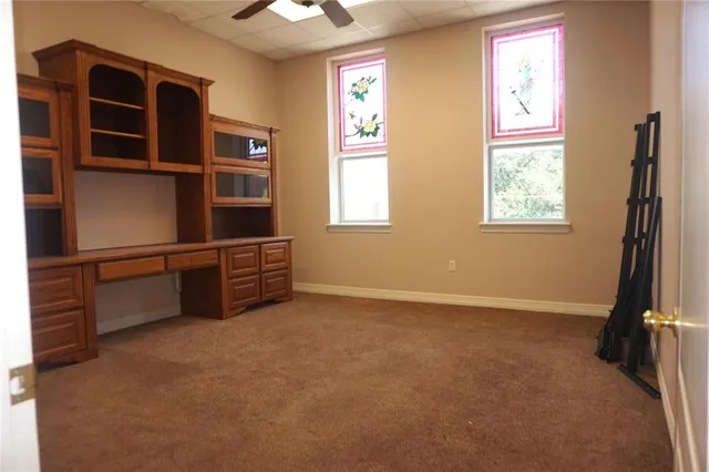 a view of an empty room with furniture and a window