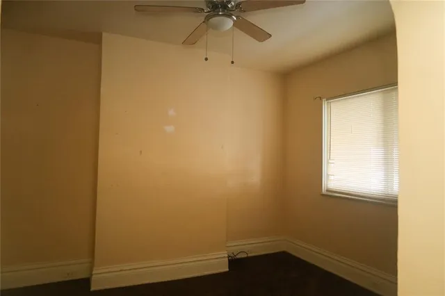 an empty room with a window and a fan