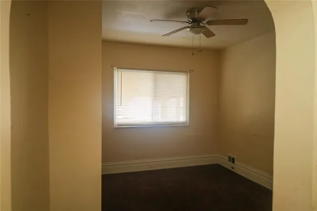 an empty room with a window and a fan