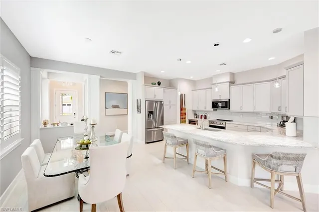 a kitchen with stainless steel appliances a table and chairs in it