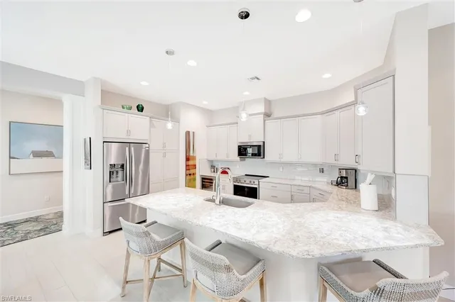 a kitchen with stainless steel appliances kitchen island granite countertop a kitchen island and chairs in it
