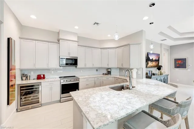 a kitchen with stainless steel appliances kitchen island granite countertop a table chairs sink and cabinets