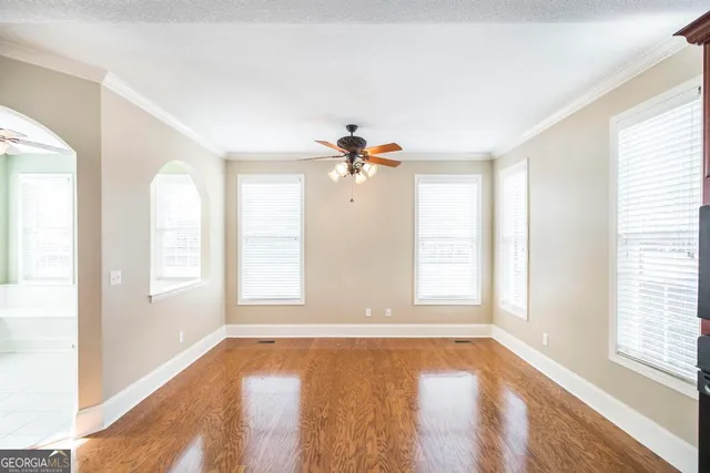 a view of empty room with wooden floor and fan