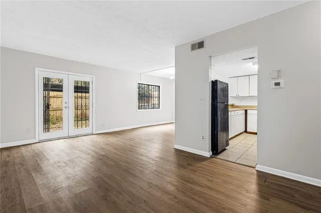 a view of a livingroom with wooden floor and a refrigerator