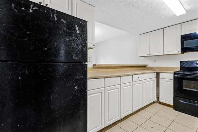 a kitchen with white cabinets and black appliances