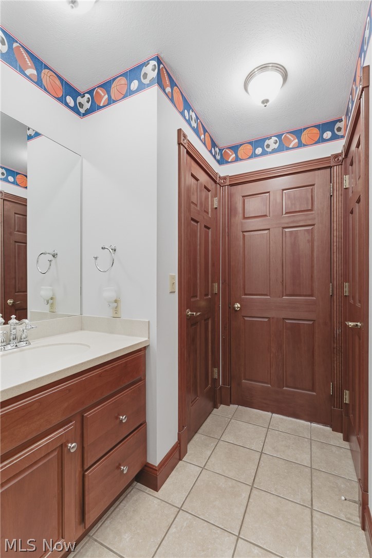 2184 Brenner Road Northeast Carrollton, OH 44615 - Photo 32 of 50 Bathroom featuring a wood-finish vanity with a light-toned countertop, a large wall-mounted mirror, and tile flooring