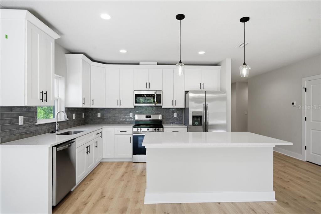 15212 Hawley Road Weeki Wachee, FL 34614 - Photo 5 of 25 a kitchen with stainless steel appliances kitchen island a sink a stove a refrigerator and cabinets