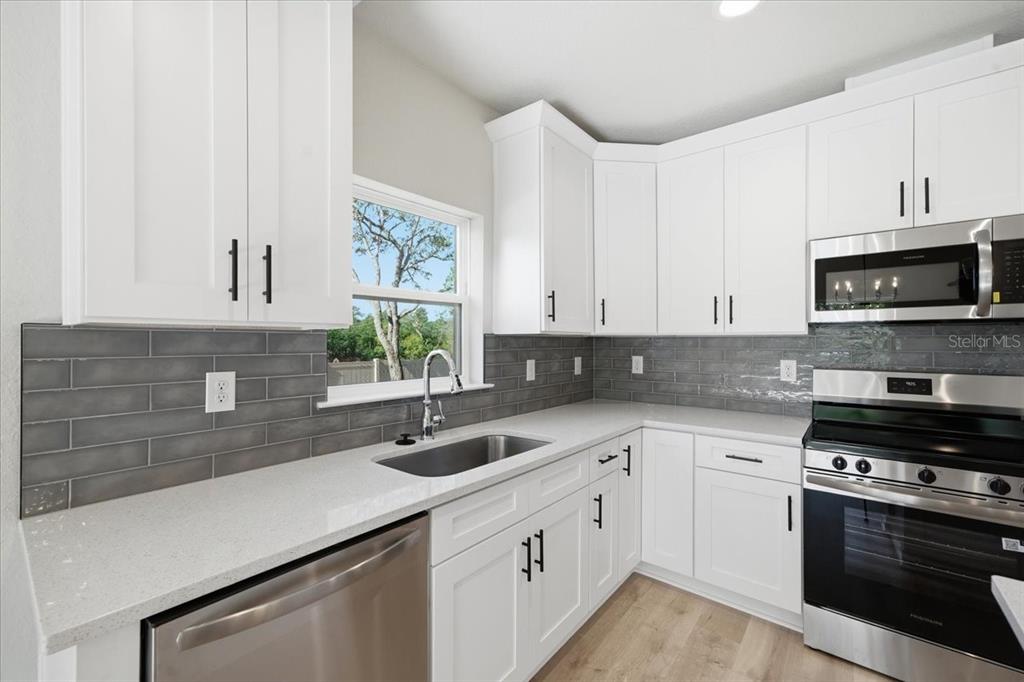 15212 Hawley Road Weeki Wachee, FL 34614 - Photo 6 of 25 a kitchen with stainless steel appliances white cabinets a sink and a stove