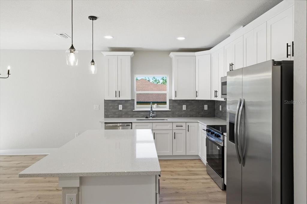 15212 Hawley Road Weeki Wachee, FL 34614 - Photo 9 of 25 a kitchen with stainless steel appliances granite countertop a refrigerator a sink and white cabinets
