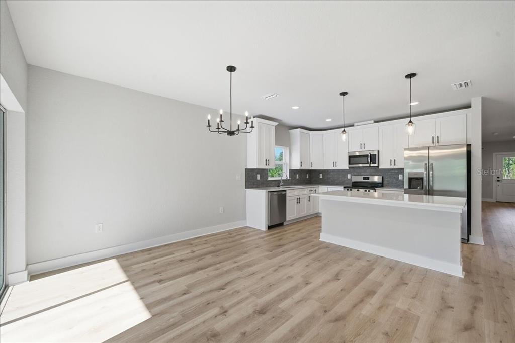 15212 Hawley Road Weeki Wachee, FL 34614 - Photo 10 of 25 a kitchen with stainless steel appliances kitchen island granite countertop a refrigerator a sink dishwasher a stove and white cabinets with wooden floor
