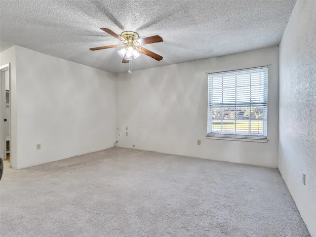 an empty room with windows and chandelier fan