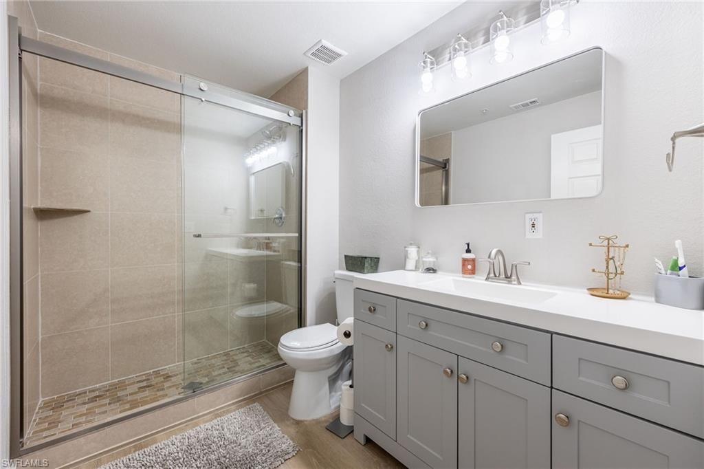 4710 St Croix Lane, Unit 216 Naples, FL 34109 - Photo 19 of 29 a bathroom with a toilet a sink a glass door a shower and a mirror