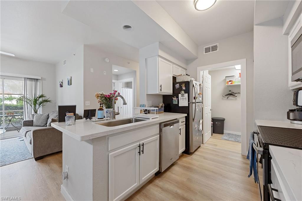 4710 St Croix Lane, Unit 216 Naples, FL 34109 - Photo 29 of 29 a large white kitchen with kitchen island a sink and a refrigerator