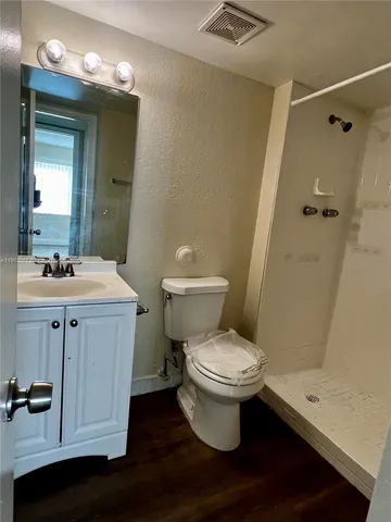 a bathroom with a sink a toilet a mirror and shower