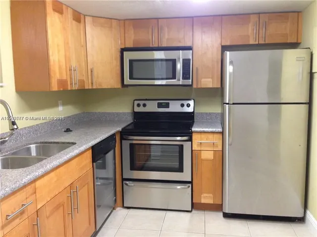a kitchen with granite countertop a refrigerator and a sink