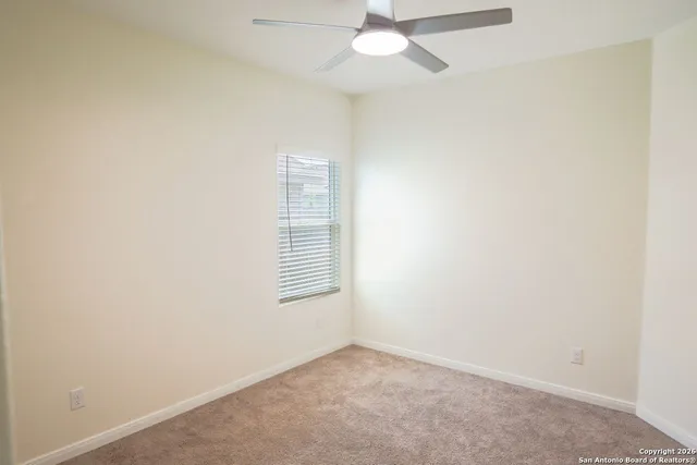 an empty room with a fan & a window