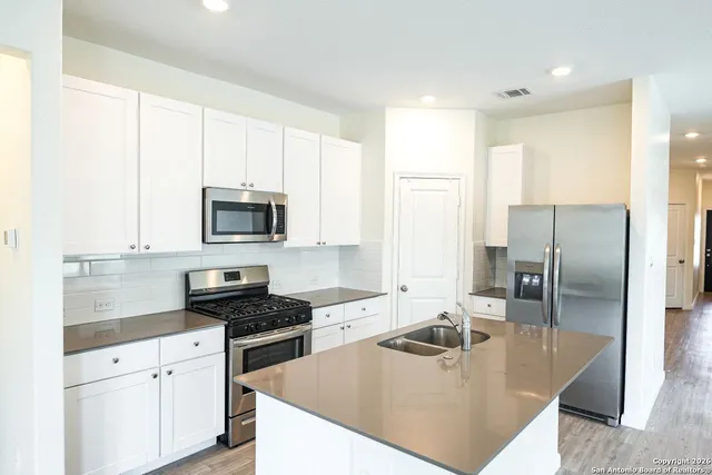 a kitchen with stainless steel appliances granite countertop a sink a stove and a refrigerator