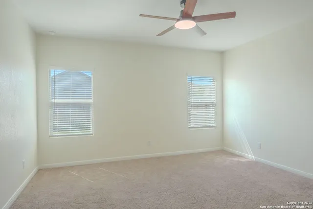 an empty room with a window and ceiling fan