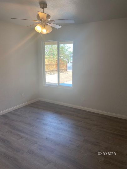 1009 West Boston Avenue Ridgecrest, CA 93555 - Photo 3 of 9 an empty room with wooden floor fan and windows