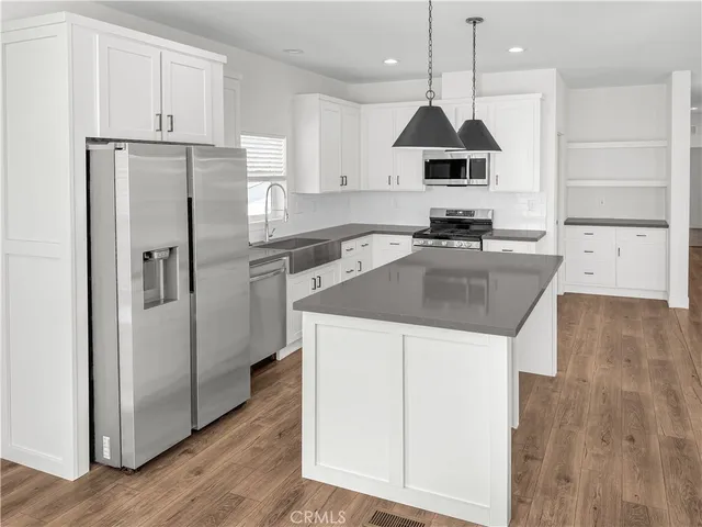 a kitchen with kitchen island granite countertop a sink counter space cabinets and stainless steel appliances
