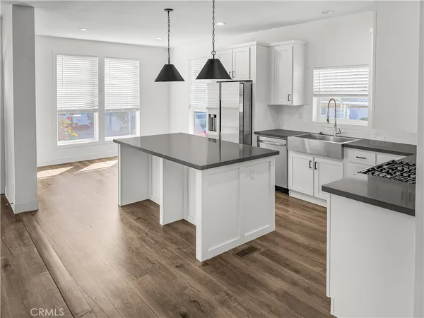 a kitchen with stainless steel appliances granite countertop a sink a stove and a wooden floors