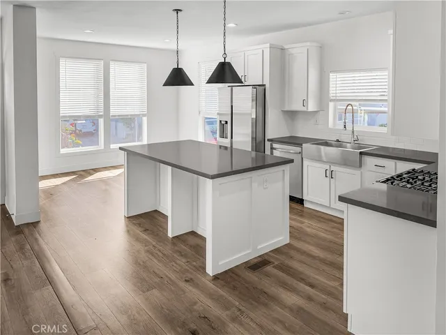 a kitchen with stainless steel appliances granite countertop a sink a stove and a wooden floors