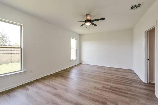 a view of empty room with wooden floor and fan