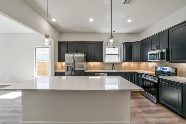 a large kitchen with granite countertop a large counter top stainless steel appliances and cabinets
