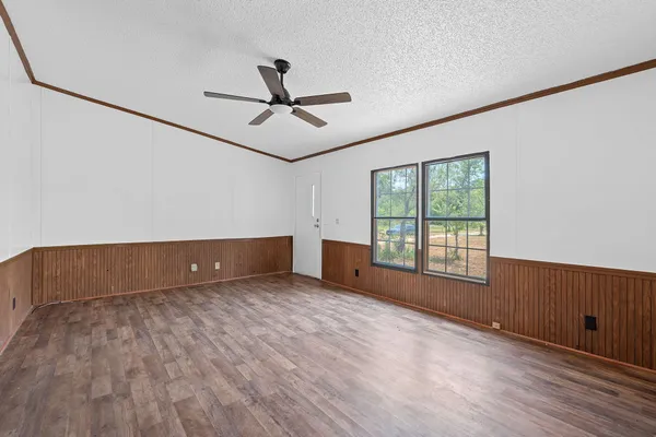 a view of an empty room with a window and wooden floor