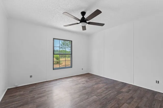 an empty room with window and ceiling fan