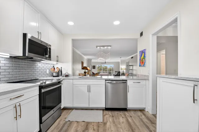 a kitchen with stainless steel appliances granite countertop a stove top oven a sink dishwasher and a refrigerator with wooden floor