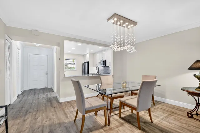a dining room with wooden floor a chandelier a wooden table and chairs
