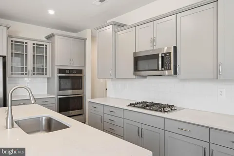 a kitchen with a sink a center island a wooden floor and a chandelier