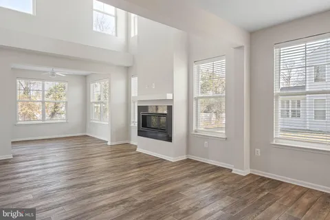 an empty room with wooden floor fireplace and windows