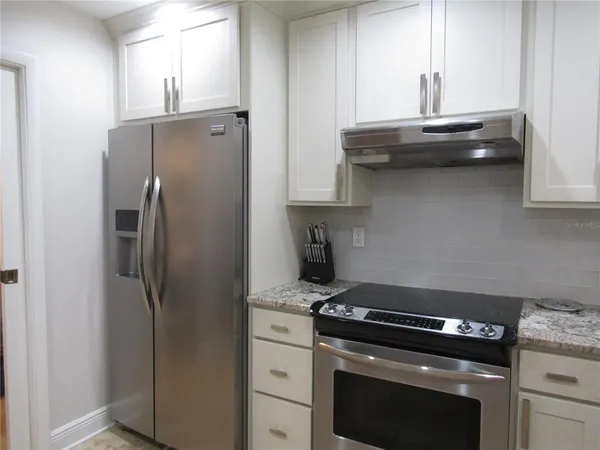 a kitchen with stainless steel appliances granite countertop a refrigerator and a stove