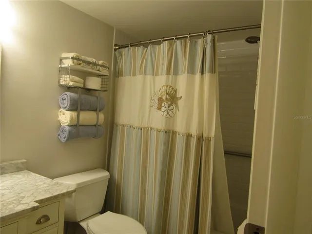 a bathroom with a granite countertop shower and a toilet