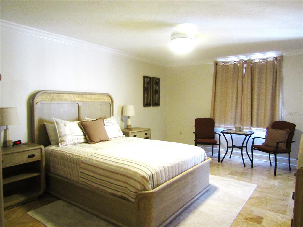 5056 Marsh Field Road, Unit 7 Sarasota, FL 34235 - Photo 27 of 31 a bedroom with a bed wooden floor and a chandelier